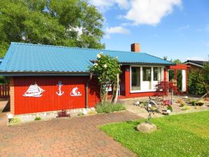 a small red house with a blue roof at Holiday home coastal dream in Schönhagen
