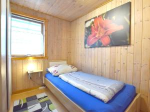 a small bedroom with a blue bed in a wooden room at Holiday home coastal dream in Schönhagen