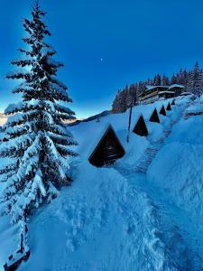 Un albero di Natale nella neve con dei rifugi di Hotel Te Liqeni a Pejë