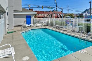 a swimming pool with chairs and a white fence at Mariners Watch 304 - Luxury Bayview Condo in Ocean City