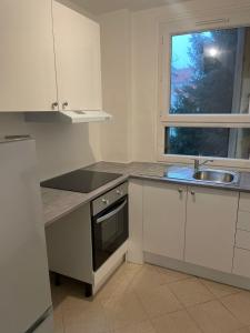 a kitchen with white cabinets and a sink and a window at 5 people/Paris-CDG/France Stadium in Bagnolet