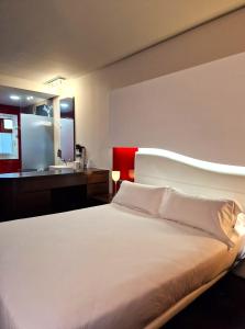 a bedroom with a large white bed and a bathroom at Hotel Maroa Vigo in Vigo
