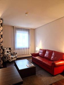 a living room with a red couch and a chair at Maroa Hotel in Vigo