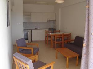 Pola Costa Beach Hotel Apts - Adults Only في بروتاراس: غرفة معيشة مع طاولة وكراسي ومطبخ