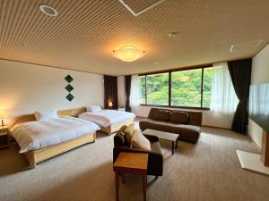 ein Hotelzimmer mit 2 Betten und einem Sofa in der Unterkunft Yuze Hotel in Kazuno
