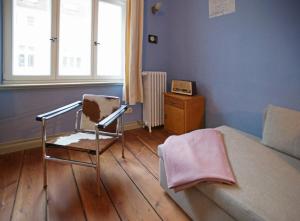 a bedroom with a chair and a bed and a window at Historisches Altstadthaus St Georgen - ABC347 in Wismar