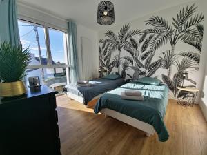 a bedroom with two beds and a mural of palm trees at 300m de la mer, villa moderne spacieuse 6-12 pers à Trévignon in Trégunc