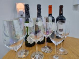 cuatro copas de vino sentadas en una mesa con botellas de vino en Sinami, en Gangneung