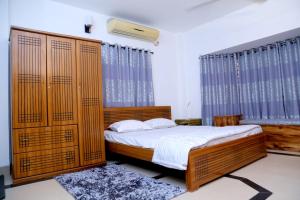 a bedroom with a large bed with wooden panels at Nirapod Holiday Home in Sylhet