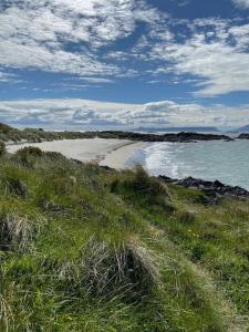 a beach with grass and the ocean and the sky at The Old Schoolhouse in Morar