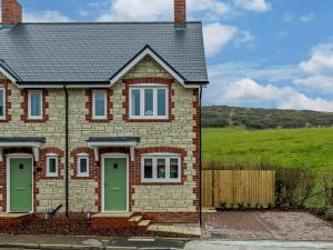 a brick house with green doors and a field at 2 Bed in Lulworth Cove 91197 in West Lulworth