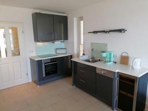 una cocina con armarios negros y fregadero en Villa Seeblick - ABC223, en Bad Kleinen