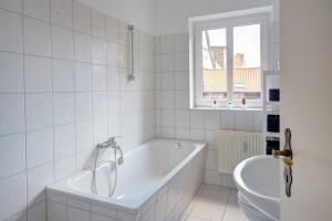 ein weißes Bad mit einer Badewanne und einem Fenster in der Unterkunft Traumfänger in Wismar