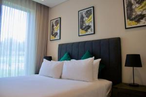 um quarto com uma cama com lençóis brancos e uma janela em Outstanding 2BR Sandton with a View em Joanesburgo