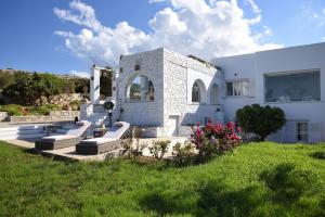 Biały dom z trawnikiem z ławkami w obiekcie Villa Agia Thalassa Beachfront Luxury Villa Ampelas Paros w mieście Paros