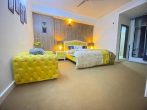 a bedroom with a bed and two yellow chairs at Viceroy Royal Hotel Apartment Islamabad in Islamabad