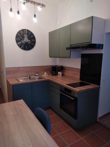 a kitchen with a sink and a clock on the wall at Mas de la Sauline in La Roque-dʼAnthéron