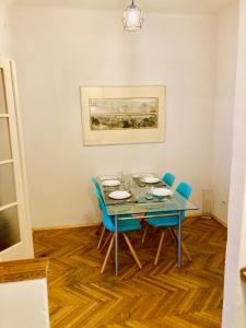 ブダペストにあるBuda Apartman near Gellértのダイニングルーム(ガラステーブル、青い椅子付)