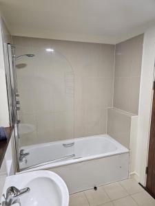 a bathroom with a shower and a tub and a sink at Penthouse Apartment in Kilkenny