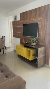 uma sala de estar com uma televisão e um armário amarelo em Apartamento bossa nova em Aracaju