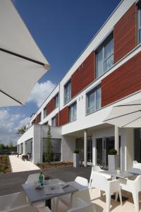 un edificio con sillas y mesas blancas delante de él en Hotel Kapellenberg en Eibelstadt