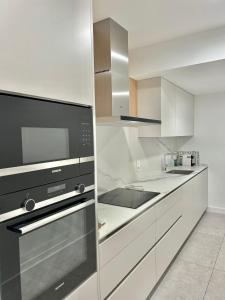 una cocina con electrodomésticos de acero inoxidable y armarios blancos en Plaza Tomás, en Pamplona
