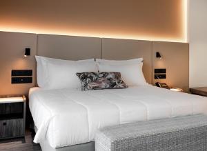 1 dormitorio con 1 cama grande con almohadas blancas en Vincci EverEden, en Anavyssos