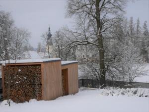 un edificio de madera en la nieve con una valla en Apartmán Sychrova, en Žďár nad Sázavou