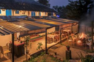 a building with a table and chairs and a fire at Wildernest retreat by ranjan in Aiju