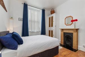 a bedroom with a bed with blue curtains and a fireplace at Penalun House - Beautiful Sea Views in Penally