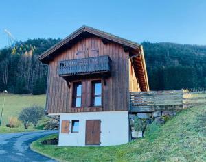 a small wooden house on a hill next to a road at Chalet La Grange in Seytroux