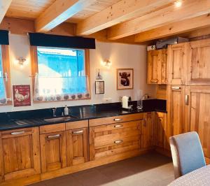 a large kitchen with wooden cabinets and a window at Chalet La Grange in Seytroux