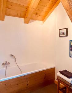 a bath tub in a room with a wooden ceiling at Chalet La Grange in Seytroux