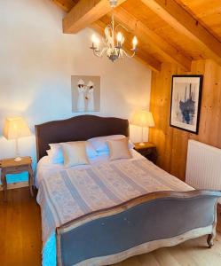 een slaapkamer met een groot bed en een kroonluchter bij Chalet La Grange in Seytroux
