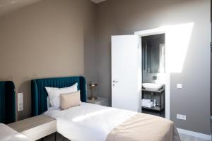 a bedroom with a white bed and a blue headboard at R.HOTEL in Chernivtsi