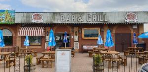 a bar and grill with wooden tables and blue umbrellas at Lazy Dayz, Chalet 179, Hemsby - Two bed chalet, sleeps 4, pet free, close to beach in Hemsby +10 photos