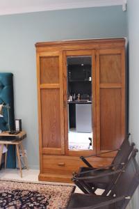 a wooden cabinet in a room with a chair at Lucano 1 Stellenbosch in Stellenbosch