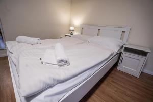 ein großes Bett mit weißer Bettwäsche und Handtüchern darauf in der Unterkunft Gogol Apartment in Szeged