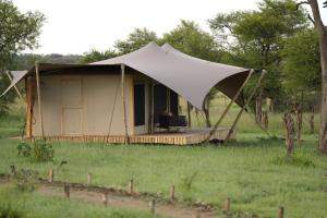 a tent with a chair in a field at Anantya Serengeti in Serengeti