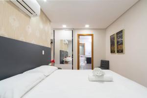 1 Schlafzimmer mit einem großen weißen Bett und einem Badezimmer in der Unterkunft Apartamento Lindo e Moderno no Centro de Gramado in Gramado