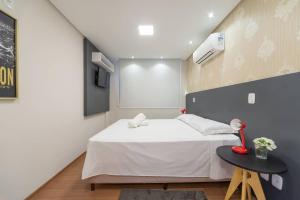a bedroom with a bed and a table with a lamp at Apartamento Lindo e Moderno no Centro de Gramado in Gramado