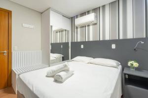 a bedroom with a white bed with towels on it at Apartamento Lindo e Moderno no Centro de Gramado in Gramado