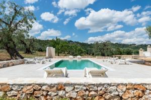 a pool with lounge chairs and a stone wall at Villa Incanto con terrazza e piscina by Wonderful Italy in Ostuni