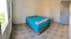 ein Schlafzimmer mit einem blauen Bett in einem Zimmer mit einem Fenster in der Unterkunft Casa com 2 quartos grandes a 150m da praia in Rio Grande