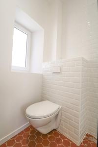 a white bathroom with a toilet and a window at Appartement cosy balcon Hypercentre in Manosque