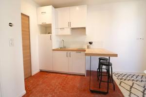 a kitchen with white cabinets and a table and stool at Appartement cosy balcon Hypercentre in Manosque