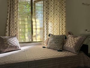 um quarto com uma cama com almofadas e uma janela em Swiss House By Keri em Varkala