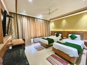 um quarto de hotel com duas camas e uma televisão de ecrã plano em Hotel ROCKBAY, Puri Swimming-pool, near-sea-beach-and-temple fully-air-conditioned-hotel with-lift-and-parking-facility em Puri
