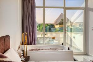 a bath tub in a room with a large window at Tree Lounge Pyramids View INN , Sphinx Giza in Cairo