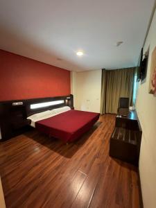 1 dormitorio con cama grande y pared roja en LA CANTUEÑA, en Madrid